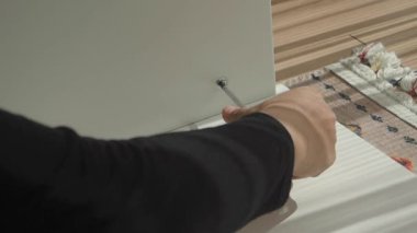 Bir kişi ahşap parçaları bir tezgahta el aletleriyle birleştiriyor..