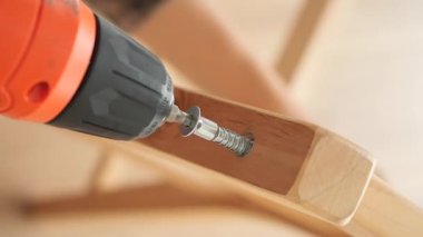 Bir insan ahşap mobilya parçalarını güvenli bir şekilde monte etmek için elektrikli matkap kullanır..