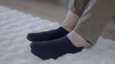 Evdeki yumuşak, tüylü halıda siyah çoraplı insan rahatlar..