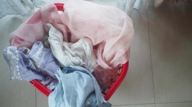 Kırmızı çamaşır sepetindeki giysiler evde yıkanmaya hazır..