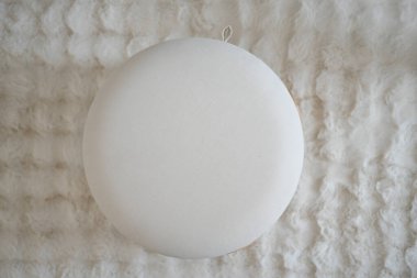 Yuvarlak beyaz bir yastık, kabarık, dokulu bir yüzeye dayanır..