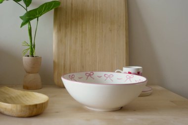 Dekoratif kase bir bitki ve fincanın yanındaki ahşap masada duruyor..