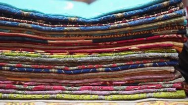 Katlanmış tekstil koleksiyonunda canlı renkler bir pazarda sergilenir.