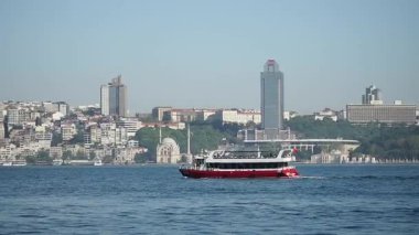 Şehir ufku ışıl ışıl parlarken, sakin sularda bir feribot seyahat ediyor..