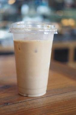 Kapalı alandaki ahşap bir masada berrak bir fincan buzlu kahve duruyor..