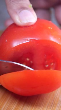 Canlı bir domatesin yemek hazırlığı için ustalıkla dilimlenişini izleyin..