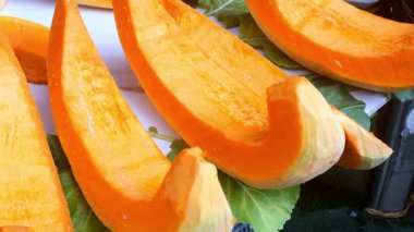 Sonbaharda hareketli bir pazarda renkli balkabağı dilimleri sergilenir.