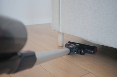 Elektrikli süpürge oturma odasındaki kanepenin altını temizlemek için kullanılır..