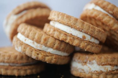 Koyu bir yüzeyde kremayla dolu çıtır kurabiyeler..