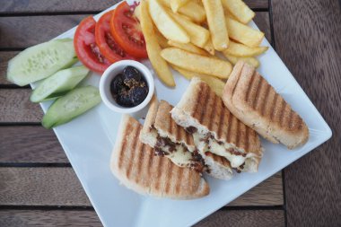 Izgara sandviç, patates kızartması ve taze sebzelerden oluşan enfes bir tabak..