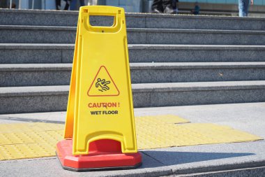 Islak zemin koşulları hakkında insanları uyarmak için basamaklara uyarı levhası asılmış..