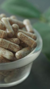 Bitkisel kapsüllerin yapraklarla dolu temiz bir kaseye yakın çekim görüntüsü..