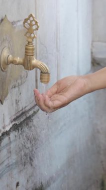 Bir el musluğun altına uzanır, sakin bir ortamda tatlı su toplar..