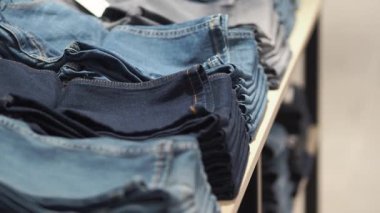 Çeşitli kot pantolonlar bir mağaza rafında düzenli olarak düzenlenir.