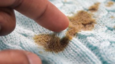 Parmak, temizlerken açık mavi örgü kumaştaki lekeye dokunur..