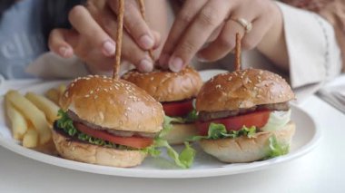 Arkadaşlar bir lokantada taze malzemeler ve patates kızartmasıyla lezzetli burgerleri paylaşırlar..