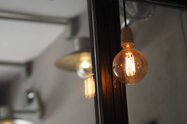 Parlayan eski model bir ampul şık bir odada asılı duruyor..