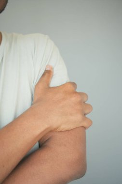 Bir insan omzunu tutuyor, muhtemelen rahatsızlığını gösteriyor..