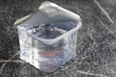 İçinde sıvı bulunan küçük, temiz bir kap karanlık bir yüzeyde duruyor..