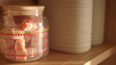 Canlandırıcı şekerlerle dolu cam bir kavanoz raftaki beyaz kavanozların yanında duruyor..