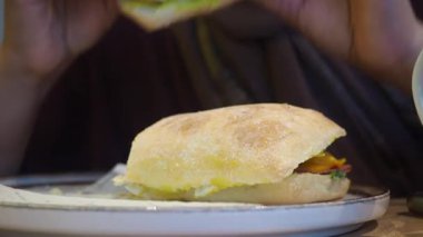 Bir insan kafede yeni yapılmış bir sandviçin tadını çıkarmaya hazırlanır..