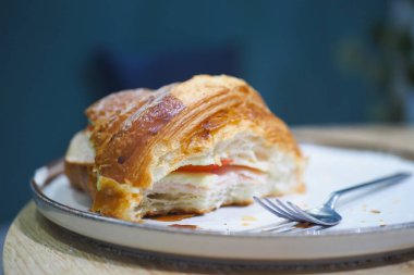 Sebzelerle dolu yarısı yenmiş bir kruvasan tabakta oturur ve lezzeti davet eder..