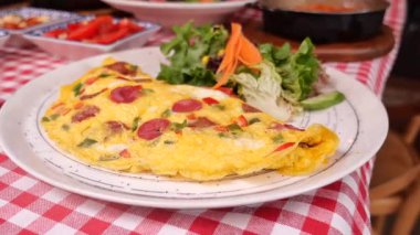 Taze salatanın yanında sebze ve etle dolu canlı bir omletin tadını çıkar..