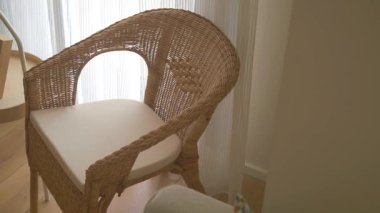 Yastıklı bir rattan sandalye sıcak bir odaya cazibe katar..