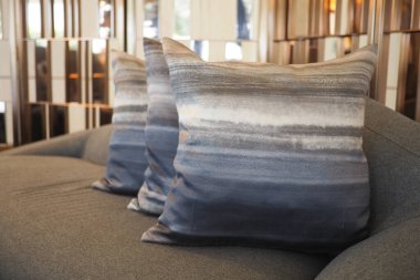 Şık bir ortamda çizgili yastıklarla süslenmiş yumuşak gri kanepe..