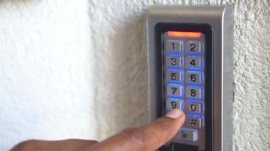 Bir kişi binanın güvenlik kodunu girmek için tuş takımı kullanıyor..