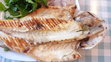 Taze yeşillik ve soğanla birlikte ızgara balık yemeğinin tadını çıkarın..