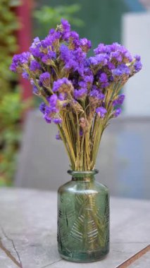 Güzel, mor, kurutulmuş çiçekler masanın üstünde yeşil bir vazoda düzenlenir..