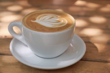 Köy tabakasında karışık yaprak tasarımlı taze demlenmiş latte..