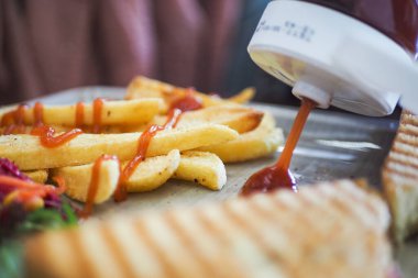 Kızarmış patates kızartması, ızgara ekmekli bir tepside ketçapla serpiştirilmiş..