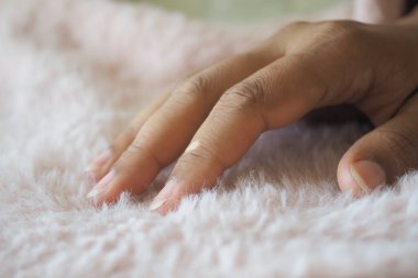 Bir el, rahat bir mekanda yumuşak pembe bir kumaşı okşar..
