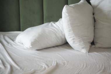 Yumuşak beyaz yastıklar yumuşak bir battaniyeyle düzgünce yapılmış bir yatağa yerleştirilir..
