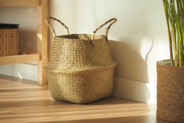 Parlak bir odada duvara yaslanmış şık bir sepet..