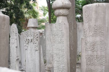 Karmaşık tasarımlı mezar taşları huzurlu bir mezarlıkta duruyor..
