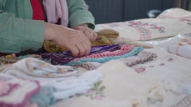 Bir satıcı canlı tekstil ve el sanatlarını bir bahar pazarında sergiler.