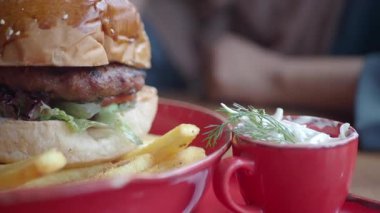 Lezzetli bir hamburgerin ve yanında kremalı sosla patates kızartmasının tadını çıkarıyorum..