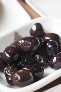 Lezzetli siyah zeytinler beyaz bir tabakta güzelce dizilmiş..