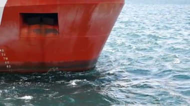 Bir kargo gemisi dalgaların arasından geçerken pürüzsüz sularda yol alır..