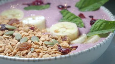 Muz ve tahıl gevreğiyle kaplı canlı bir meyve suyu kasesinin tadını çıkar..