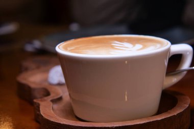 Latte sanatıyla sıcak bir latte bir kafedeki ahşap tepside duruyor..