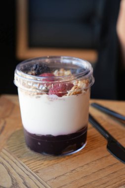 Tahta bir masada taze böğürtlen ve granola katmanlı yoğurt parfe..