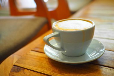 Kafedeki ahşap bir masada bir fincan taze kahvenin tadını çıkarıyorum..