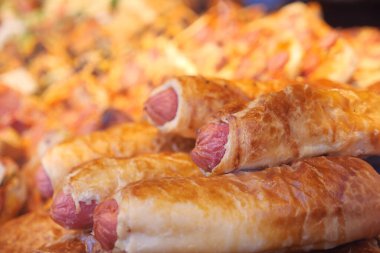 Canlı bir gıda pazarında sergilenen lezzetli sosisli börekler..