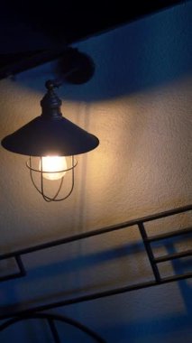 Kırsal bir metal lamba, geceleri duvarda sıcak bir parıltı bırakır..