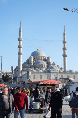 Kalabalık, berrak mavi gökyüzünün altındaki görkemli bir caminin önünde toplanıyor..