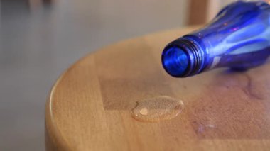 Mavi bir şişe devrildi ve ahşap yüzeye sıvı dökülmesine neden oldu..